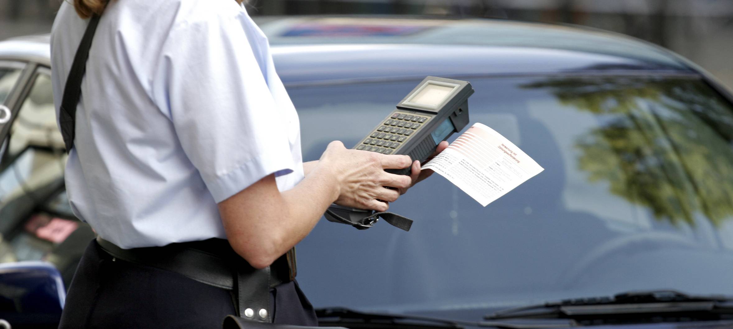 Eine Politesse stellt einem Parksünder ein Bußgeld aus (Symbolbild).
