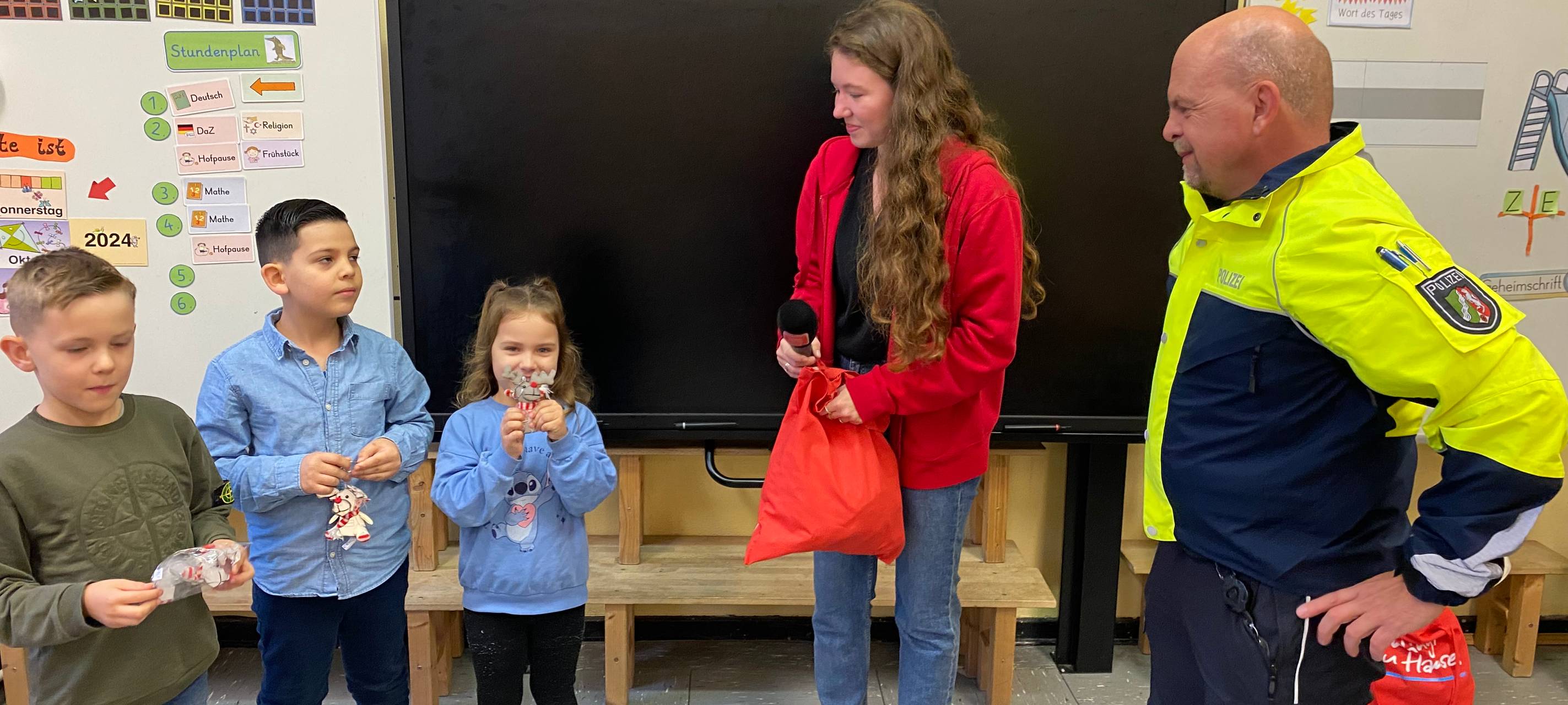 Eine Radioreporterin und ein Polizist sprechen in einem Klassenraum zu Kindern. | Foto: Zoé Kozlowski / Radio Herne