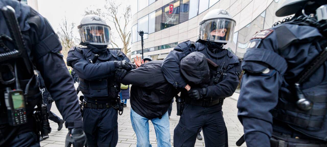 Polizeibeamte überwältigen einen Mann am Rande einer AFD-Kundgebung und Gegenprotesten.