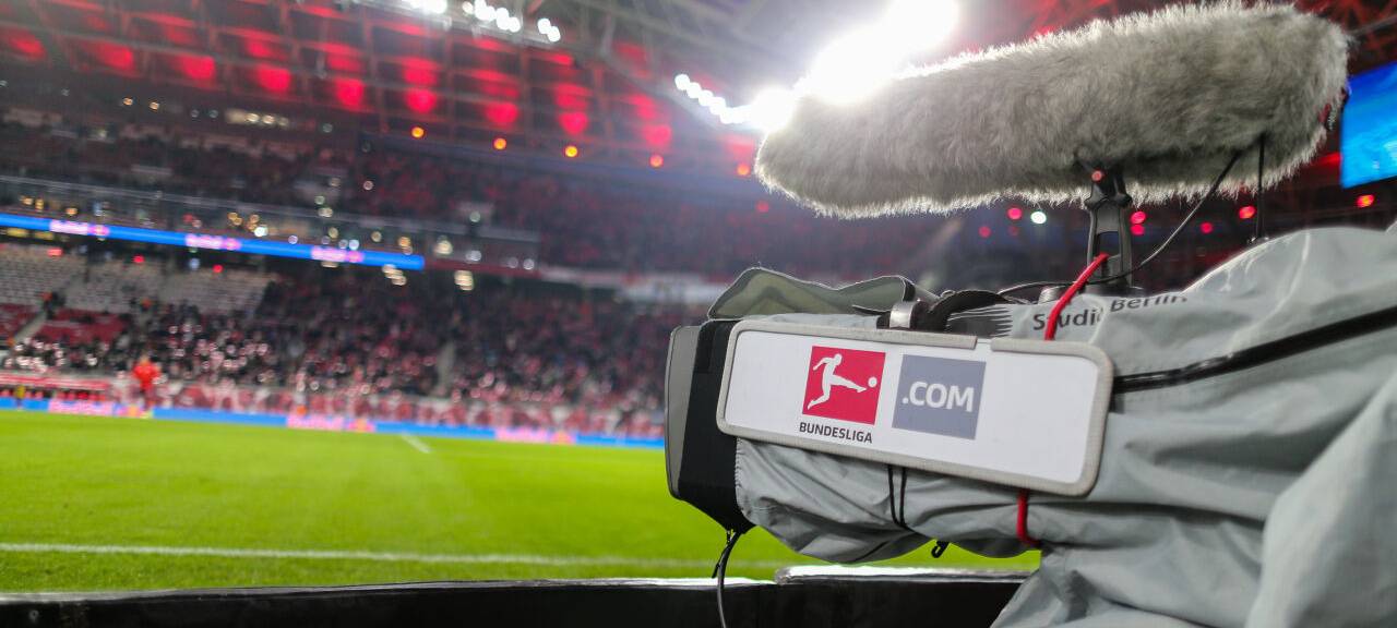 Eine Fernsehkamera ist am Spielfeldrand eines Bundesliga-Stadions zu sehen.