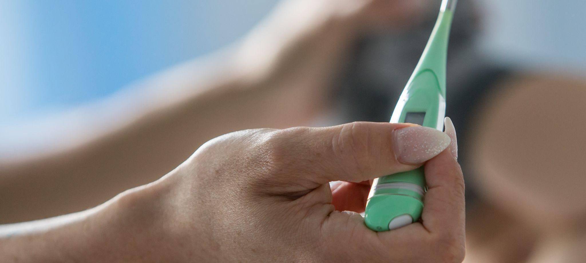 Eine Mutter misst bei einem Säugling Fieber