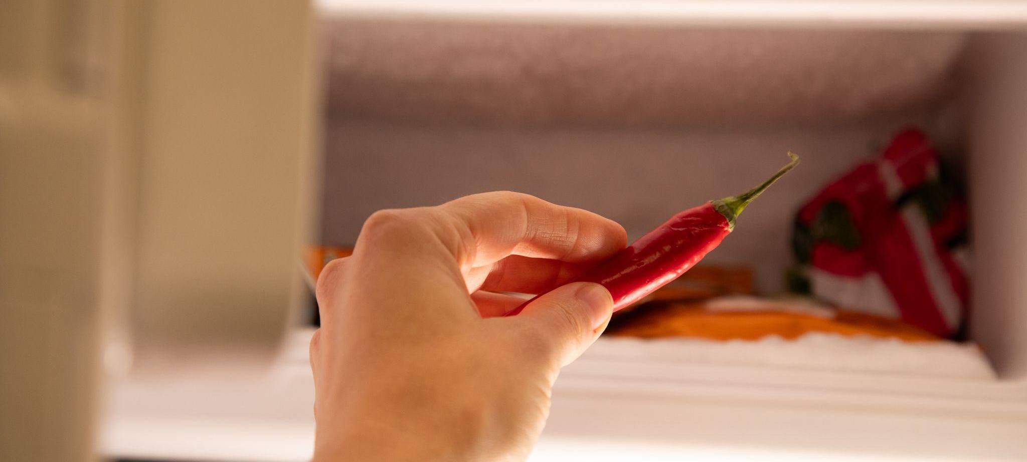 Eine Frau legt eine Chili in ein Eisfach