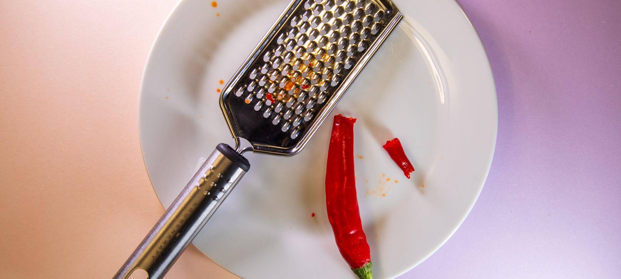 Gebrochene Chili liegt neben einer Küchenreibe