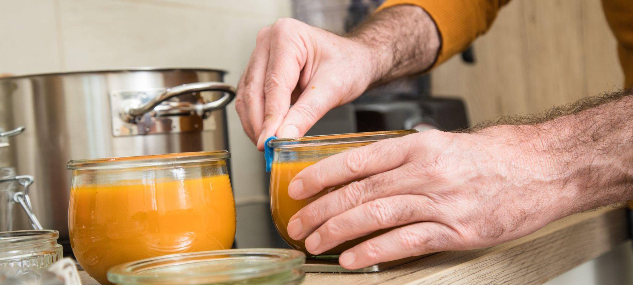 Ein Mann füllt Kürbismuß in Einweckgläser
