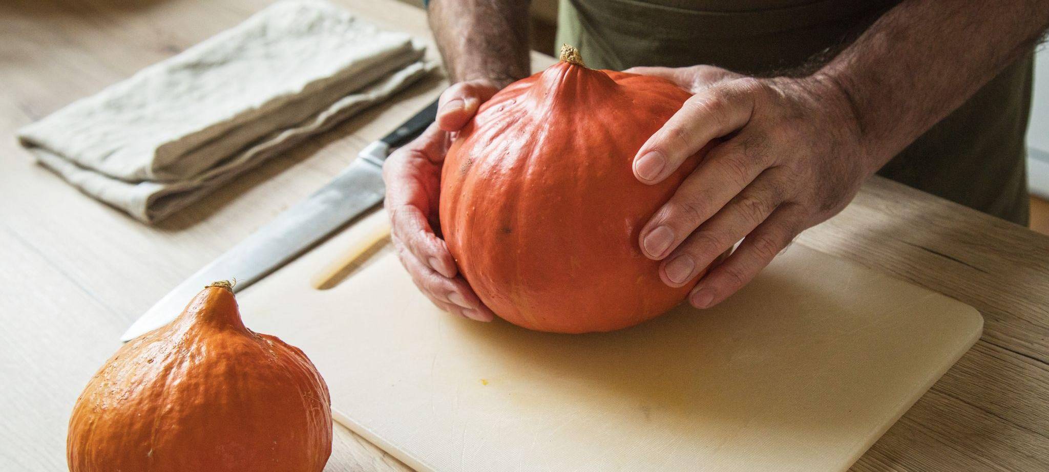 Ein Mann hält einen Hokkaido-Kürbis in den Händen