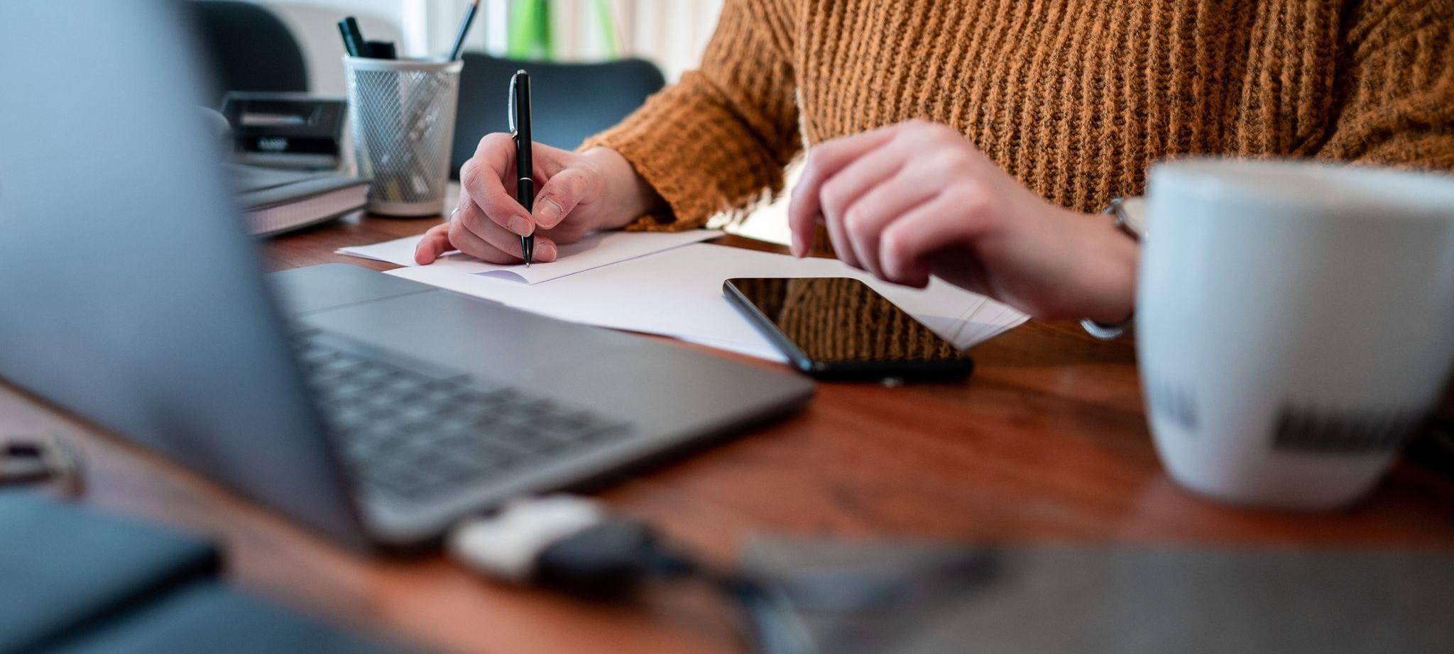 Frau sitzt mit einem Laptop am Tisch