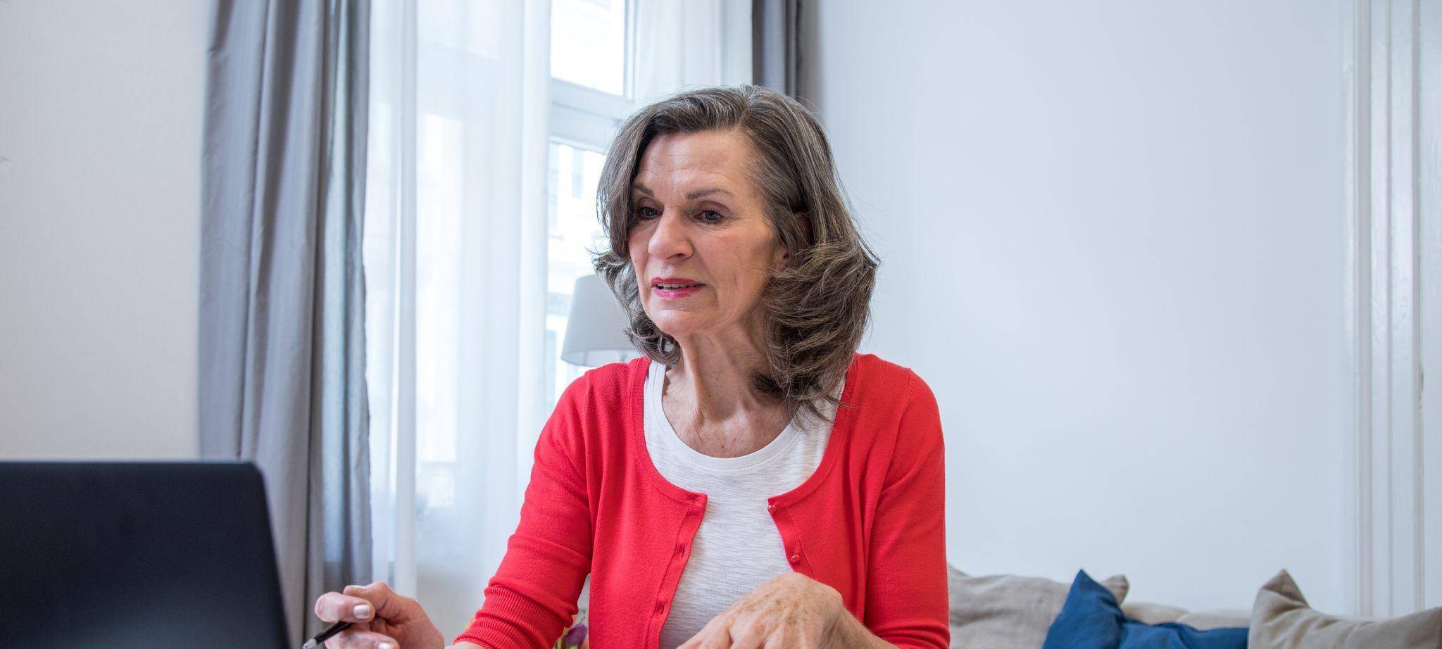 Eine ältere Frau arbeitet am Laptop.