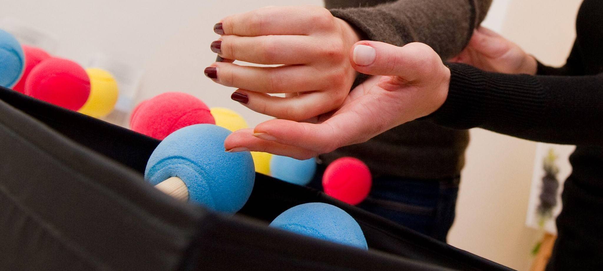 Eine Ergotherapeutin trainiert die Hand einer Patientin