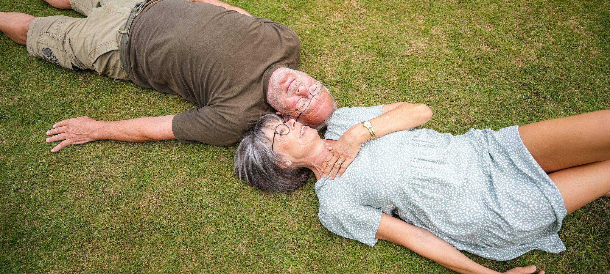 Ein älteres Paerchen liegt in einem Garten