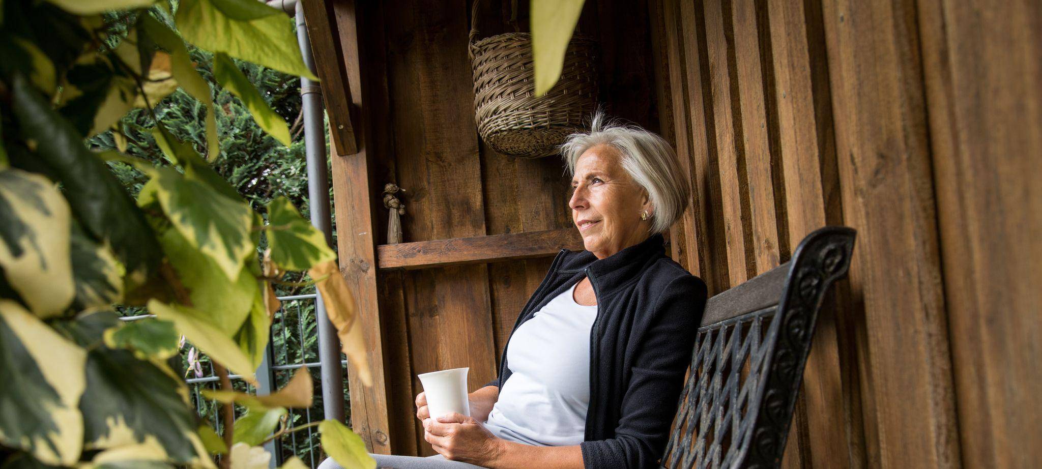 Eine ältere Dame sitzt in einem Garten