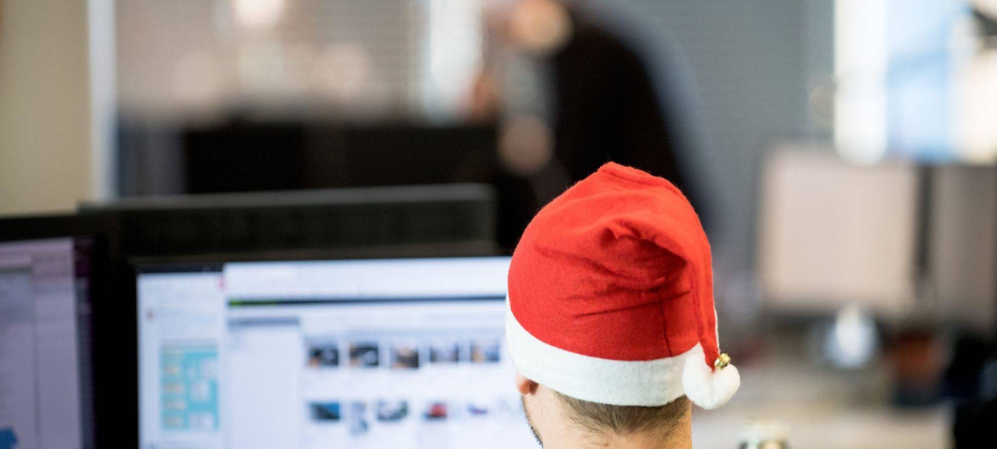 Ein Mann sitzt mit Weihnachtsmütze im Büro