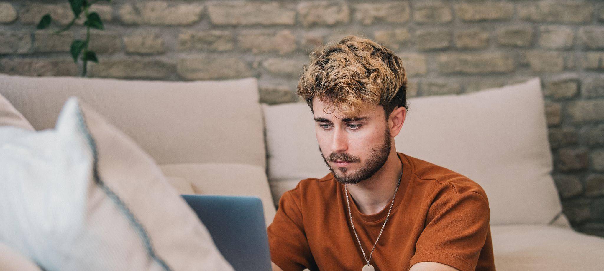 Ein Mann am Laptop auf einer Couch