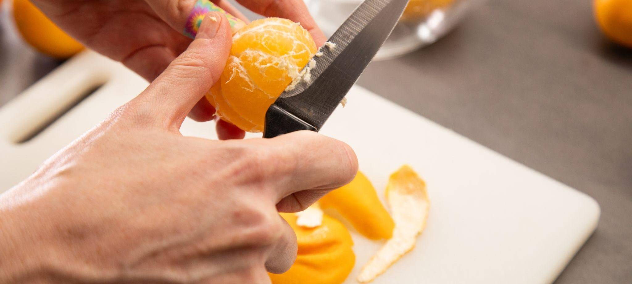 Clementinen werden mit einem Messer von den weißen Fäden befreit