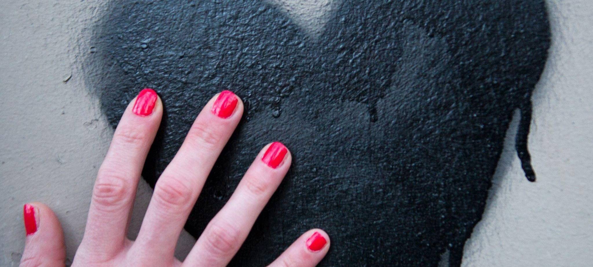 Frauenhand berührt ein auf die Wand gesprühtes Herz