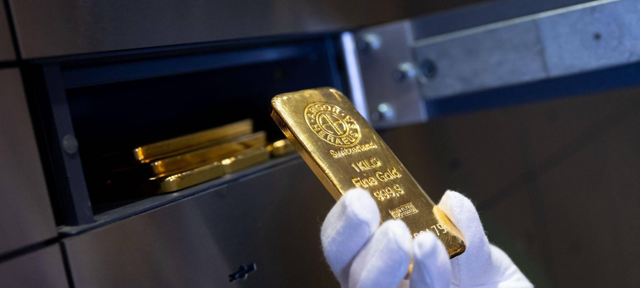 Mann legt einen Goldbarren in ein Schließfach eines Tresorraums