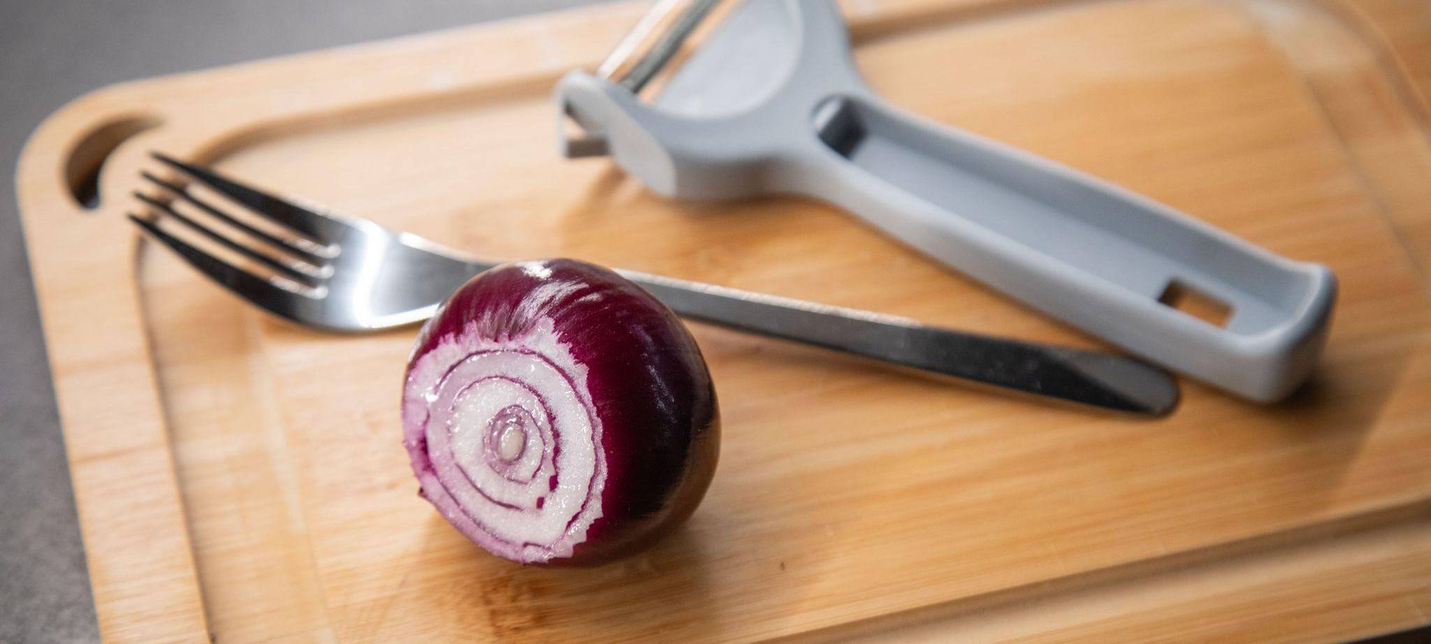 Zwiebel und ein Sparschäler liegen auf einem Tisch