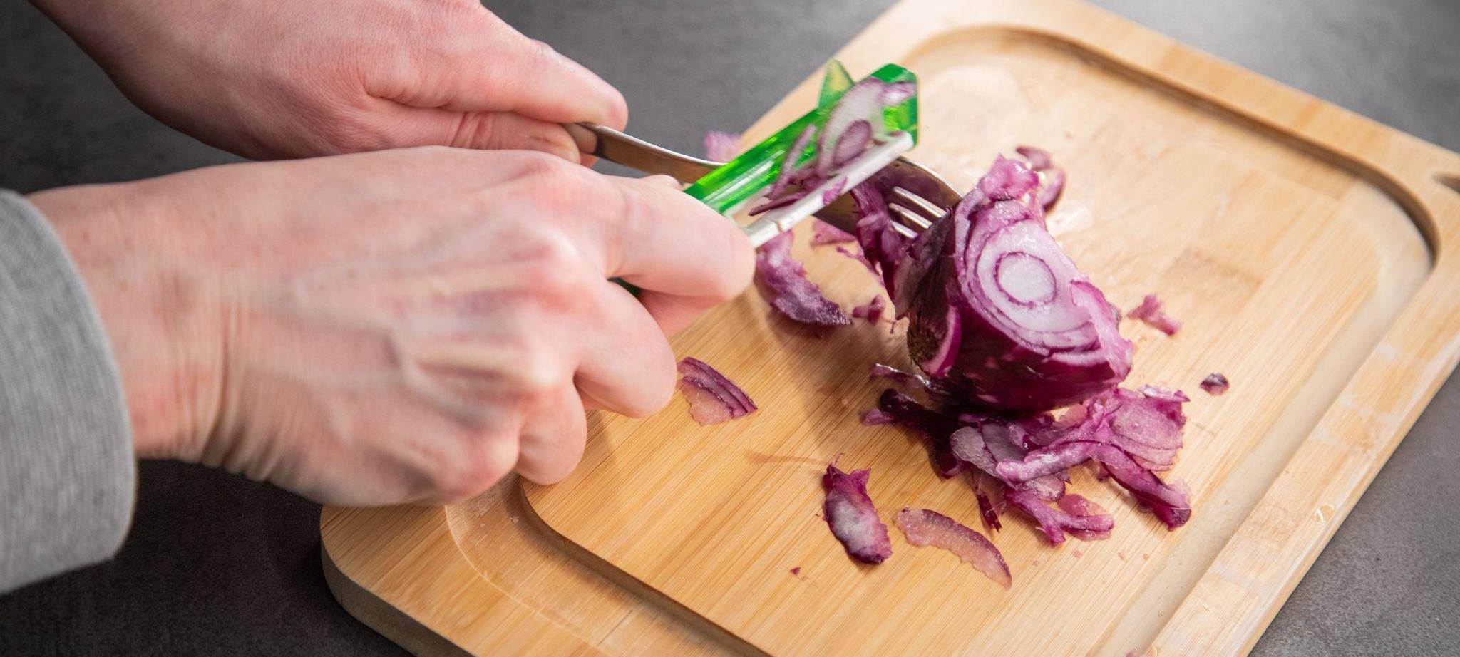 Ein Sparschäler wird über eine Zwiebel gezogen