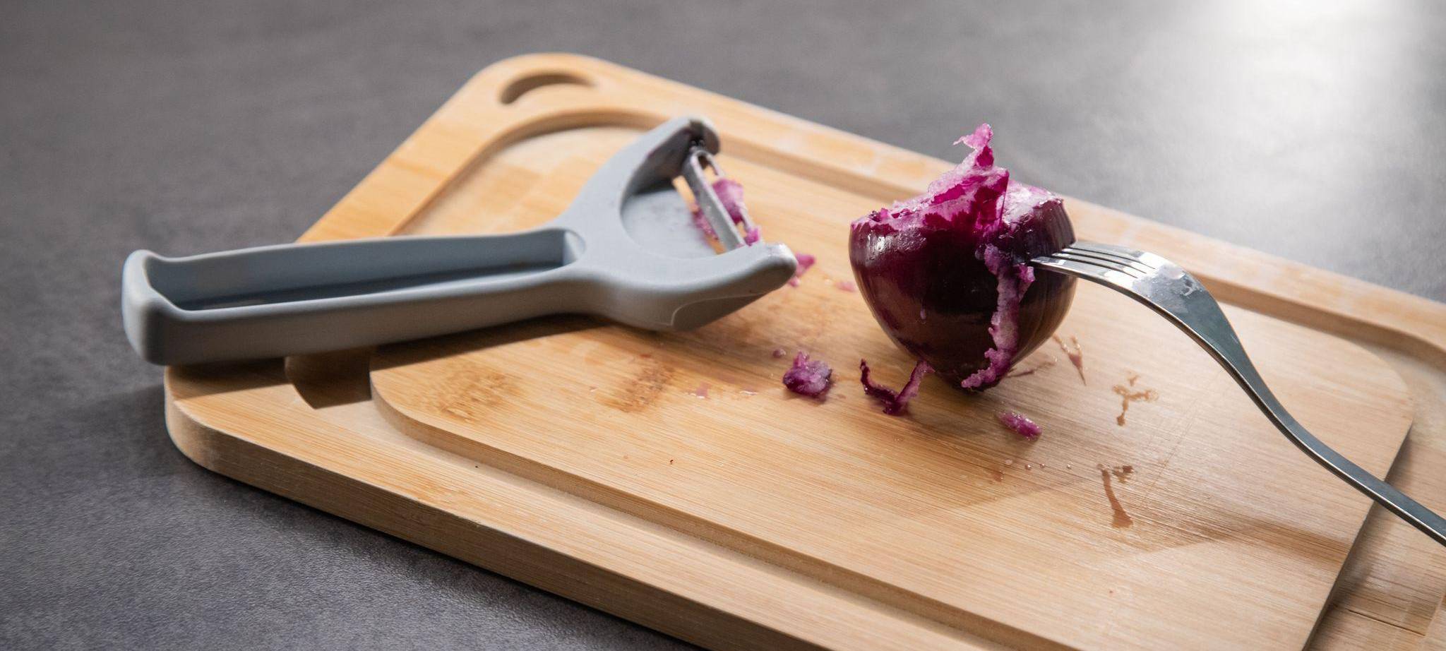 Sparschäler liegt neben einer Zwiebel