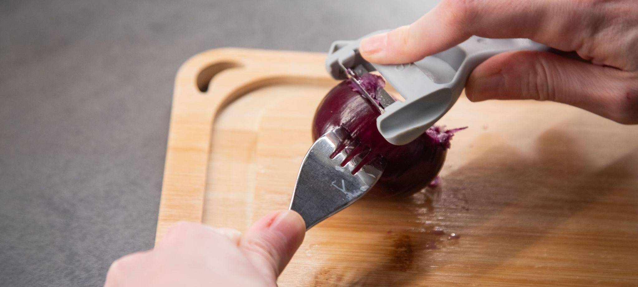 Ein Sparschäler wird über eine Zwiebel gezogen